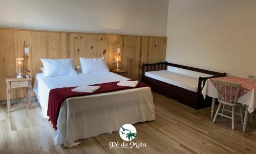 a bedroom with a large bed and a table and a bed and a bedskirts at Pousada Pé da Mata Maresias in Maresias