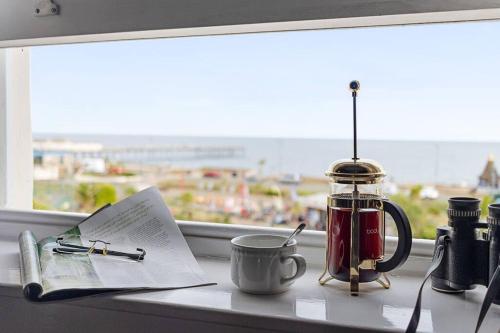 a window sill with a cup of coffee and a book and a cup of coffee at Modern 1 Bed Apartment, Sea Views, free parking, wifi, netflix in Teignmouth