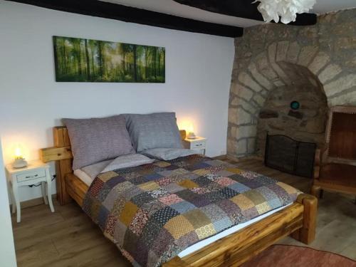 sypialnia z łóżkiem i kamiennym kominkiem w obiekcie Keltike apartman w mieście Nagybörzsöny
