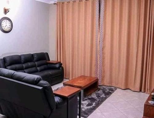 ein Wohnzimmer mit einem schwarzen Ledersofa und einem Tisch in der Unterkunft 2BHK Apartments in Kampala