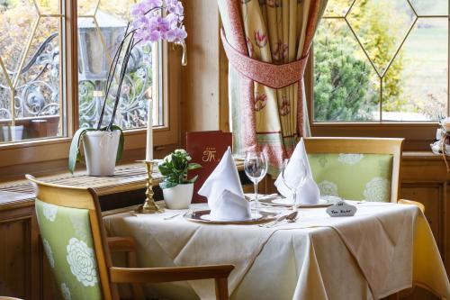 a table with a white tablecloth and two chairs and windows at Hotel Thomahof in Hinterzarten