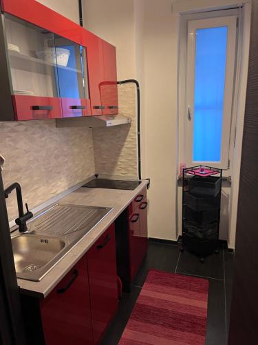 a kitchen with red cabinets and a sink at Minardi Apartments in Vercelli