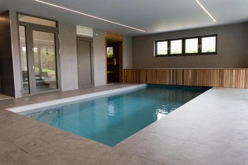 a swimming pool in a house with blue water at Gite Kooa Prestige in Theux