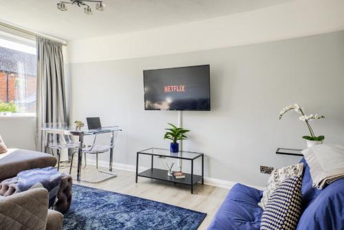 a living room with a couch and a tv on the wall at Town Centre Apartment in Leamington Spa