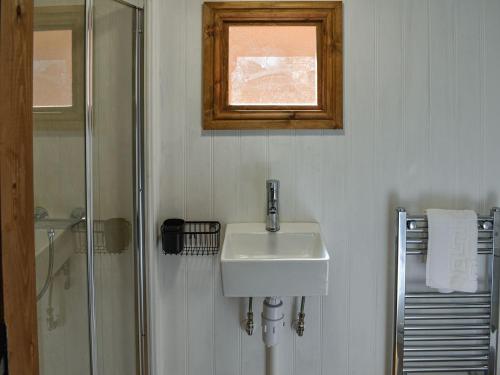 a white bathroom with a sink and a shower at Keldholme Shepherds Hut in Kirkbymoorside