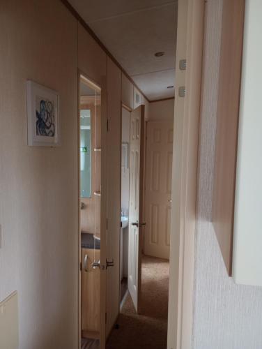 pasillo con puerta a un baño con lavabo en B58 is a 3 bedroom 8 berth caravan close to the beach on Whitehouse Leisure Park Towyn near Rhyl with private parking space This is a pet free caravan, en Abergele