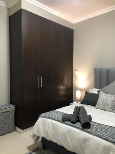 a bedroom with a large bed with brown cabinets at Meridian Suite Apartments in Umhlanga Ridge in Durban