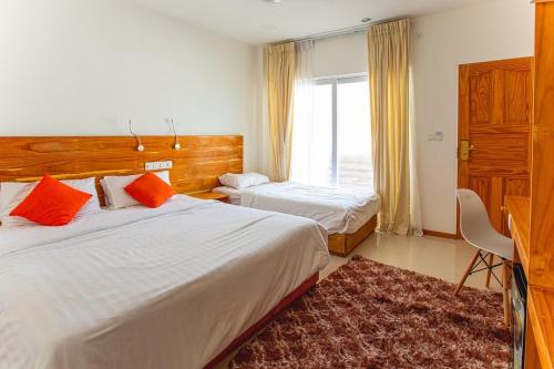 a hotel room with two beds and a window at Alaika Maafushi in Maafushi