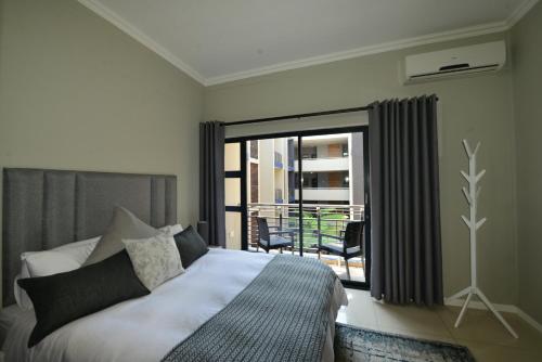 a bedroom with a bed and a window with a balcony at Meridian Suite Apartments in Umhlanga Ridge in Durban