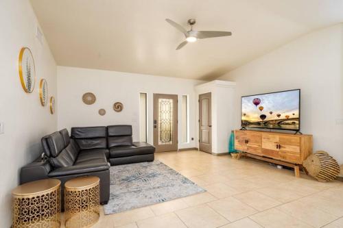 a living room with a black leather couch and a flat screen tv at Heated Pool & Spa - Winterhavens Oasis in Lake Havasu City