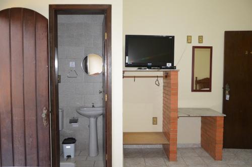 a bathroom with a sink and a tv on a wall at Hotel Colonial in Pôrto Real