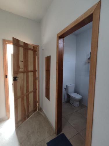 a bathroom with a toilet and a wooden door at Dom Jaime - Guest House in Pirenópolis