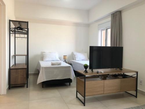 uma sala de estar com televisão e uma cama em Apartamento Wi-fi, Split, Estacionamento e Piscina em Ribeirão Preto