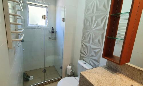 a bathroom with a toilet and a glass shower at Apto Encantador Próximo ao Centro de Gramado in Gramado