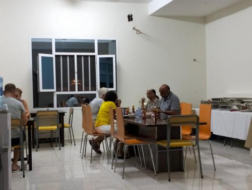 a group of people sitting at a table in a restaurant at Turtle Guest House in Sur