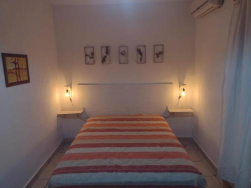 1 cama en una habitación con 2 luces en la pared en Departamentos Tierra Colorada en La Rioja