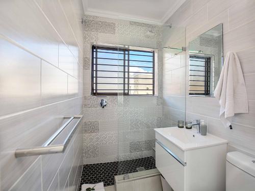 a white bathroom with a toilet and a sink at Sea Breeze Apartments in Bloubergstrand