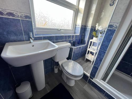 baño con lavabo y aseo y ventana en Seaside 2 bedroom house with large garden, en Rhyl
