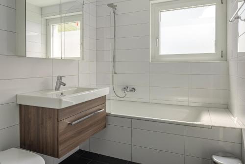 a white bathroom with a sink and a bath tub at Bella Vista in Fieschertal