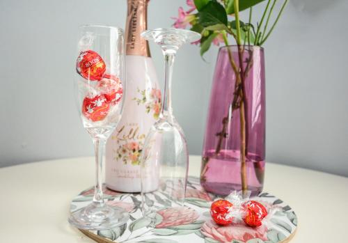 stół z dwoma kieliszkami do wina i innymi wazami w obiekcie Sea Breeze Apartments w mieście Bloubergstrand