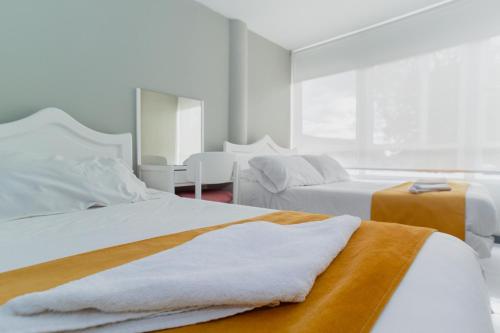 1 dormitorio con 2 camas y mesa en ApartaSuites & Hotel Bogota Suamox, en Bogotá