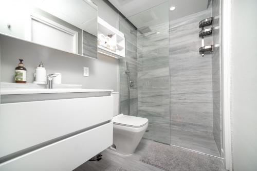 a white bathroom with a toilet and a shower at Luxury 1 bed apartment near Seven Mile Beach at The Grove - Villa Deluxe in Upper Land