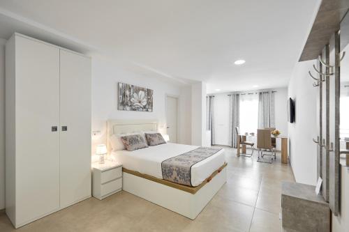 a white bedroom with a bed and a desk at Sonrisa Deluxe Apartments, Levante in Benidorm