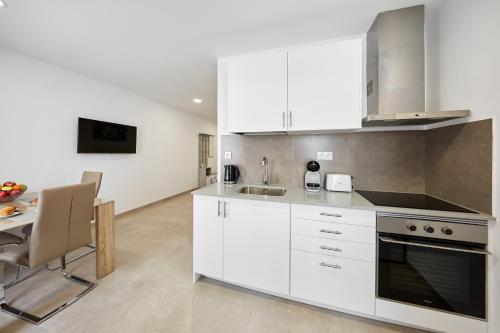 a kitchen with white cabinets and a table and a dining room at Sonrisa Deluxe Apartments, Levante in Benidorm