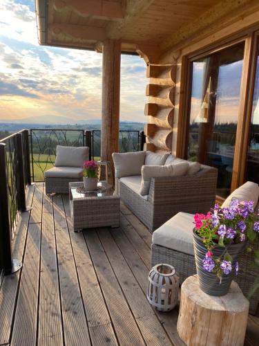 a porch with couches and flowers on a deck at Little House in Ząb