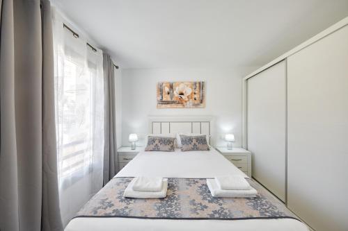 a white bedroom with a bed and a window at Sonrisa Deluxe Apartments, Levante in Benidorm