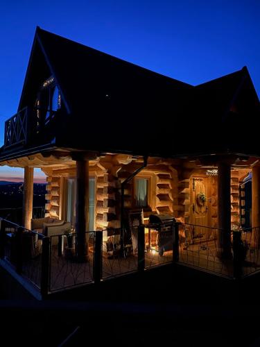 a log cabin with a deck at night at Little House in Ząb