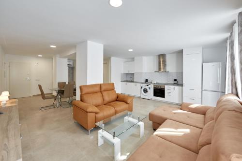a living room with a couch and chairs and a kitchen at Sonrisa Deluxe Apartments, Levante in Benidorm