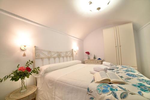 a white bedroom with a bed with a book on it at Casa Cueva Los Mosaicos in Guadix