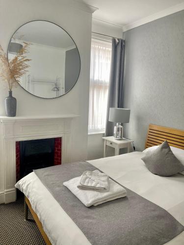 a bedroom with a bed with a mirror and a fireplace at Aragon House in Peterborough