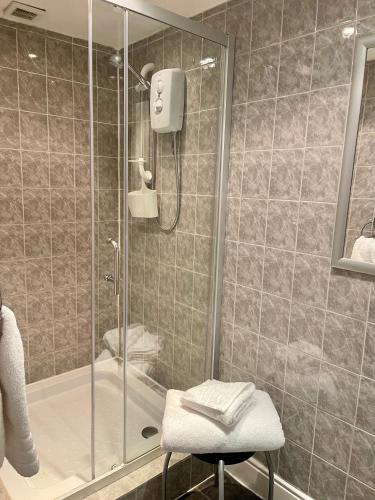 a bathroom with a shower and a stool in front of a shower at Aragon House in Peterborough