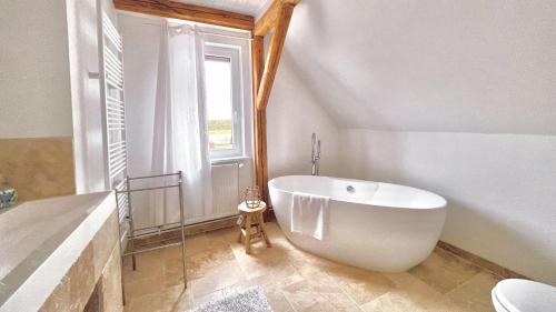 baño con una gran bañera blanca y una ventana en Historisches Amtshaus: BelVue, en Fehmarn