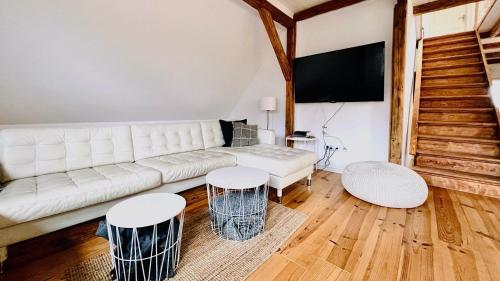 a living room with a white couch and two stools at Historisches Amtshaus: BelVue in Fehmarn