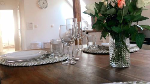 a table with wine glasses and a vase of flowers at Historisches Amtshaus: BelVue in Fehmarn