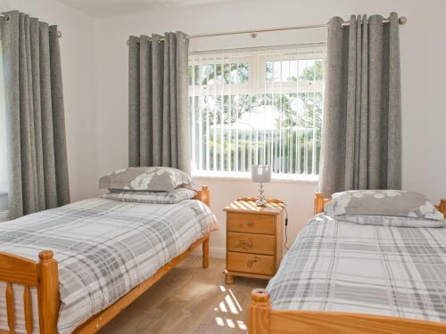 a bedroom with two twin beds and a window at Maple Cottage in Drumshanbo-Glebe