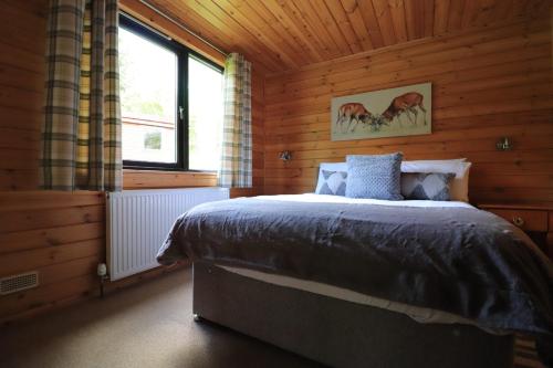 a bedroom with a bed in a wooden cabin at Balquhidder Braes Holiday Park Lodges, mostly with Hot Tubs and pet friendly, EV facilities in Lochearnhead
