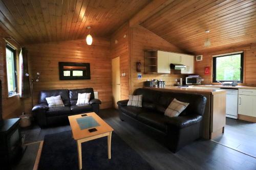 a living room with two leather couches and a table at Balquhidder Braes Holiday Park in Lochearnhead