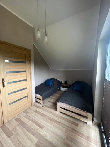 two beds in a small room with a door at Nova 26 in Klucze