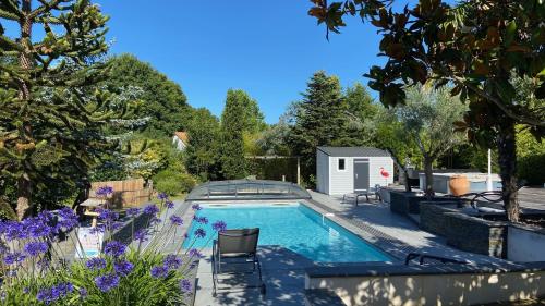 une piscine dans un jardin avec des fleurs violettes dans l'établissement Adorable Guest House avec balnéo et piscine, à Olonne-sur-Mer