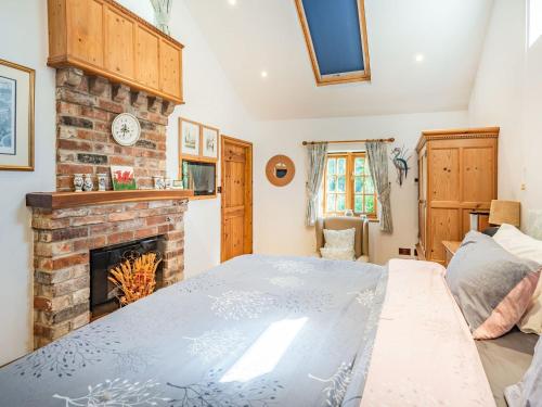 ein Schlafzimmer mit einem großen Bett und einem Kamin in der Unterkunft Kingfisher Cottage in Barkston