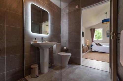 a bathroom with a sink and a mirror and a bedroom at The Rose Suite Kenmare in Kenmare