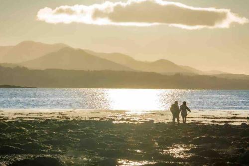 two people standing on a beach near the water at The Rose Suite Kenmare in Kenmare