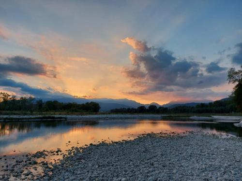 a sunset over a river with mountains in the background at Locazione Turistica El Sghirlo in Vidor