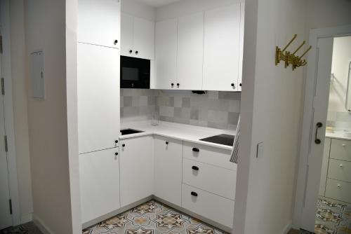a white kitchen with white cabinets and a tile floor at Apartamento Turístico El Soportal de la Plaza in Daimiel
