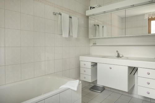 a white bathroom with a tub and a sink at Dorothy Sunshine in Fiesch
