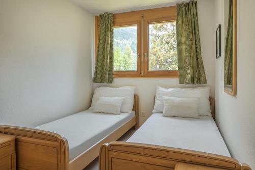 two beds in a room with two windows at Dorothy Sunshine in Fiesch